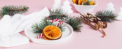 Christmas table setting lollipop, fir tree and dried orange on plate on table web banner photo