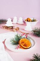 Christmas table setting lollipop, fir tree and dried orange on plate on table vertical view photo