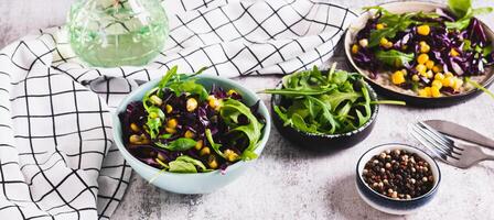Red cabbage, corn and arugula salad in a bowl on the table web banner photo
