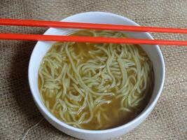instant noodle soup in a white ceramic bowl. red chopsticks. photo