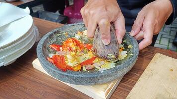 Grinding the spices with a mortar and pestle from a stone on a wooden table photo