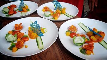 four plate Seafood Prawns in Red Sauce with Spicy Potato garnished with fresh cucumber photo