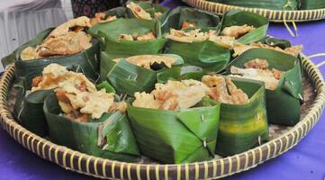 Rice and Side Dishes wrapped in banana leaves served on a bamboo plate photo