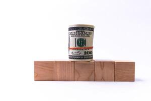Wooden cubes in the form of steps rising upwards and a roll of American dollars. Financial pyramid. Copy space. photo