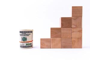 Wooden cubes in the form of steps rising upwards and a roll of American dollars. Financial pyramid. Copy space. photo