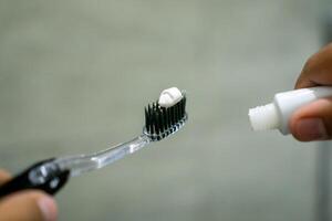 Close up of a hand holding a toothbrush with a toothpaste on the top. Oral cleaning concept. photo