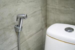 Close up of chromium bidet shower in a toilet. Handheld bidet in bathroom. photo