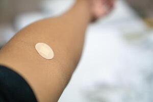Close up of medical tape on hand.. A medical adhesive bandage is placed on the injection site after blood sample collection to prevent bleeding and maintain cleanliness. photo