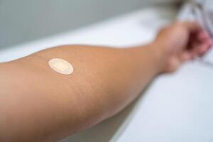 Close up of medical tape on hand.. A medical adhesive bandage is placed on the injection site after blood sample collection to prevent bleeding and maintain cleanliness. photo