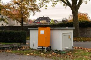 Orange utility box surrounded by autumn scenery in a residential area photo