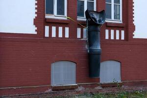 Unusual outdoor installation with black downspout on building wall photo