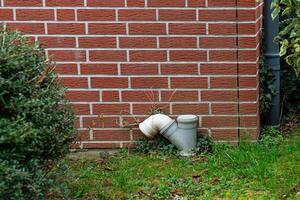 Drainage pipe with grass near brick wall in garden area photo