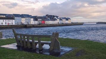 Irish cityscape sunrise scenery with old wooden boat in Corrib river at Claddagh in Galway city, Ireland, architecture background photo
