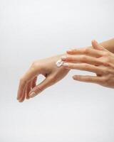 female hands apply cream one on top of the other on a white background photo