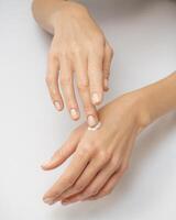 female hands apply cream one on top of the other on a white background photo