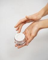 female hands hold a jar of cream on a white background photo