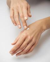 female hands apply cream one on top of the other on a white background photo