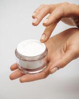 female hands hold a jar of cream on a white background photo