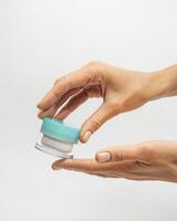female hands hold a jar of cream on a white background photo