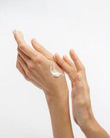 female hands apply cream one on top of the other on a white background photo