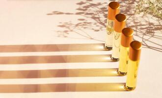 Oil perfume in travel bottles on a beige background with copy space, shadow from flowers. photo