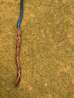 blue cable with stripped copper core on yellow floor photo
