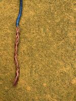 blue cable with stripped copper core on yellow floor photo