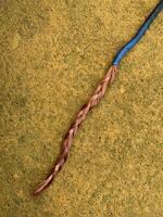 blue cable with stripped copper core on yellow floor photo