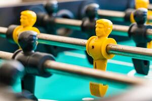 Close-Up of Yellow and Black Foosball Players on a Table with a Vibrant Green Background Highlighting Teamwork and Competitive Spirit photo