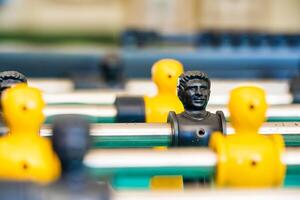 Close-Up of Yellow and Black Foosball Players on a Table with a Vibrant Green Background Highlighting Teamwork and Competitive Spirit photo
