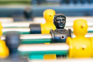 Close-Up of Yellow and Black Foosball Players on a Table with a Vibrant Green Background Highlighting Teamwork and Competitive Spirit photo