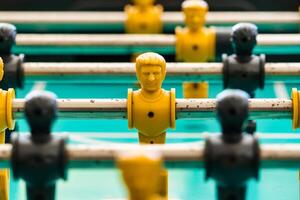 Close-Up of Yellow and Black Foosball Players on a Table with a Vibrant Green Background Highlighting Teamwork and Competitive Spirit photo