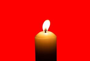 A single burning candle flame or light glowing on a big white candle isolated on red background with clipping path photo