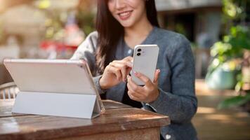 A cropped image of a woman using her smartphone while working remotely at an outdoor cafe table. photo