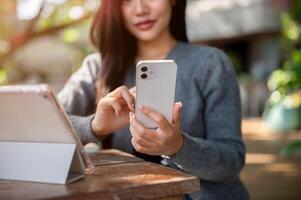 A cropped image of a woman using her smartphone while working remotely at an outdoor cafe table. photo