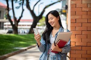A happy Asian female college student enjoys a call while heading to class on campus. photo