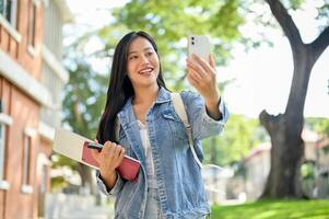 A happy Asian female college student enjoys a call while heading to class on campus. photo