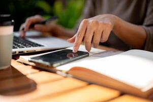 A close-up of a woman touching on her smartphone screen while working at an outdoor table. photo