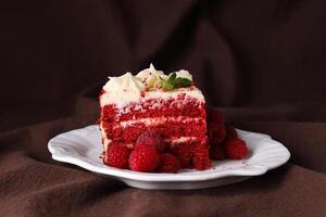 Piece of red velvet cake and berries on plate on brown background photo