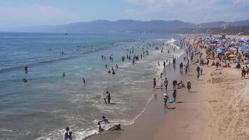 Vibrant Scene at Venice Beach with Colorful Umbrellas and Mountains video