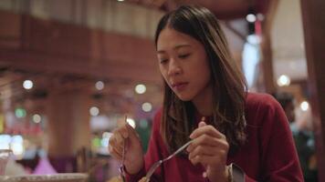 un delicioso contento momento. un joven mujer en un rojo blusa disfruta un delicioso comida con un contento sonrisa y un satisfecho expresión en un calentar restaurante atmósfera. video