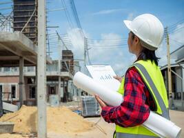 Woman engineer working at site of a large building project, Foreman holding blueprint project working outdoors building side with blueprints on a worksite, Engineering and architecture concept. photo