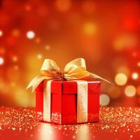 close up gift box in red wrapping paper wrapped with gold glitter ribbon on red tabletop on orange red background with bokeh photo