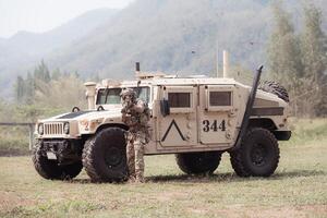 Soldiers in camouflage uniforms hold weapons ready to fire, By hiding on the side military communication vehicle photo