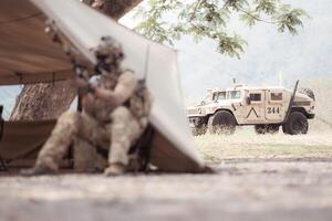 Portrait of soldiers in camouflage uniforms hold weapons in front of a field tent, Prepare for combat training photo