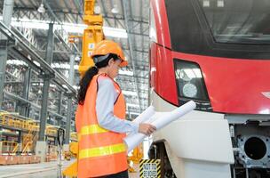 Portrait of a young female technician using a blueprint working and standing in a skytrain repair station. photo