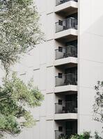 A modern apartment building with a minimalist facade featuring multiple balconies with black metal railings photo