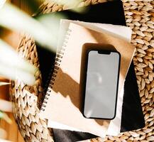 Blank path screen mobile phone with mockup on various notepads in sunlight with shadows photo