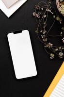 Modern smartphone on black table background with fragile houseplant and notepads photo