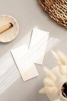 Flat lay of two blank cards sheet on aesthetic pastel grey background with plants and palo santo on sunlight background with shadow photo
